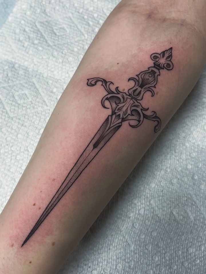 Fine line ornate floral dagger tattoo on forearm